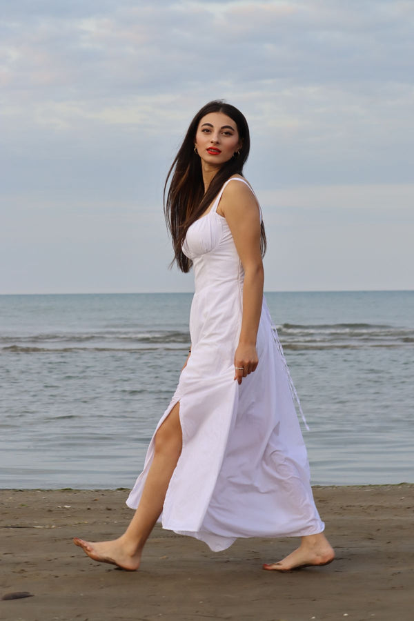 Mujer con vestido blanco caminando por la playa