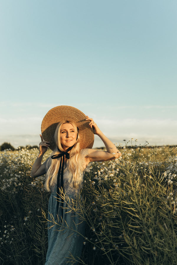 Mujer con vestido blanco y sombrero en un campo de flores