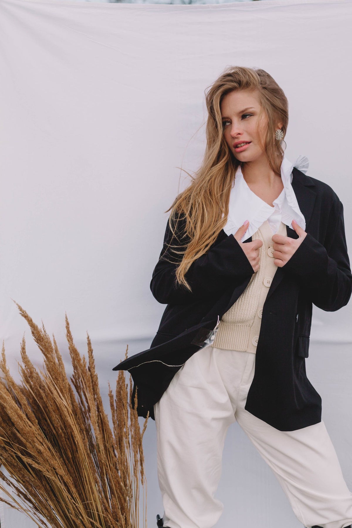 Mujer con blazer negro, camisa blanca y pantalón beige