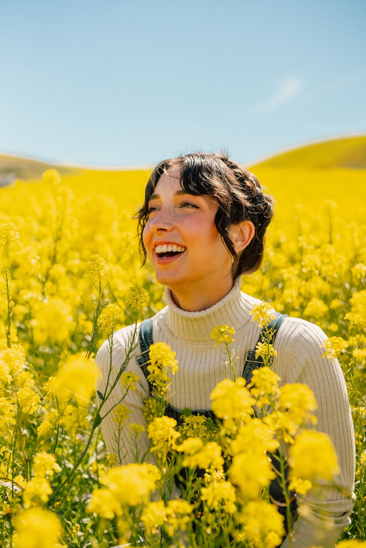 Mujer sonriendo en un campo de flores amarillas